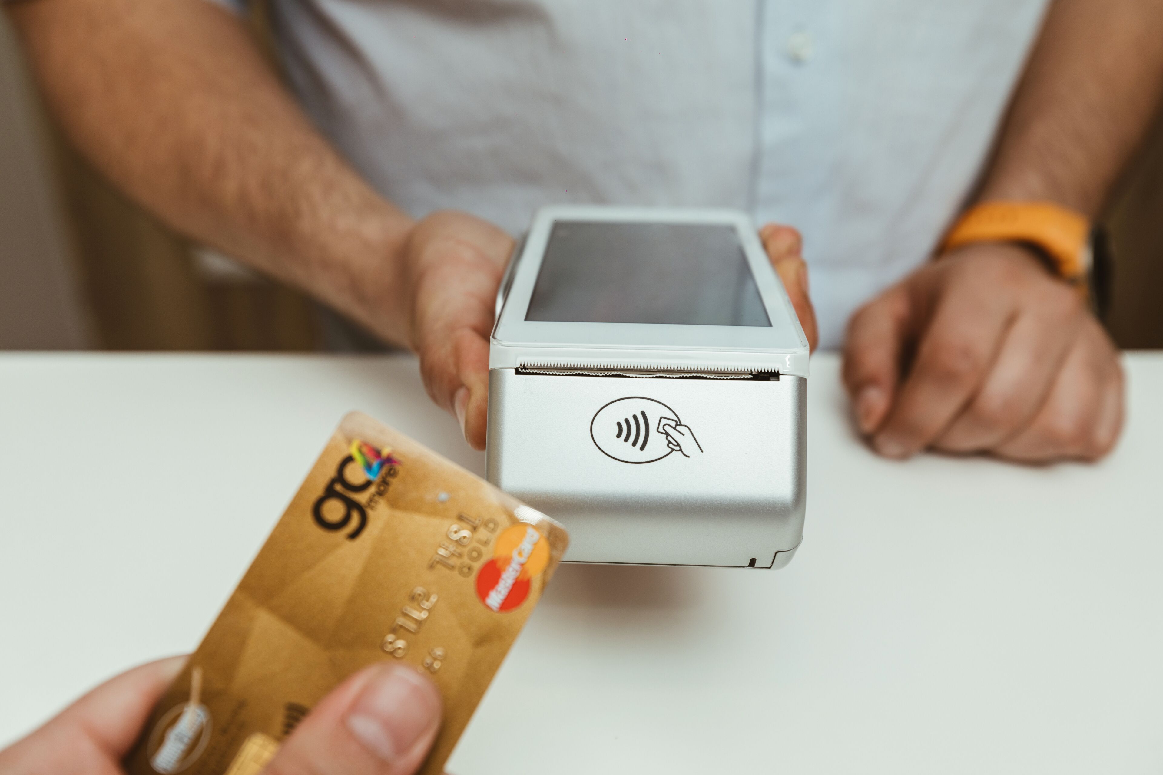 Una persona sosteniendo una tarjeta y un terminal de pago.