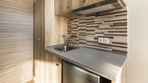 A modern kitchen with wooden cabinets, a stainless steel sink, and a dishwasher. - Sunshine Apartments (Dio-Olympos)