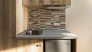 A modern kitchen with wooden cabinets, a stainless steel sink, and a dishwasher. - Sunshine Apartments (Dio-Olympos)