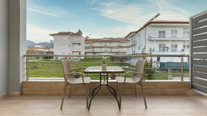 A balcony with a table and chairs, overlooking a residential area with buildings and a clear sky. - Sunshine Apartments (Dio-Olympos)