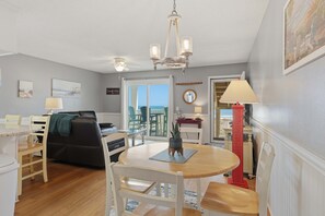 A modern living room with a dining area, a view of the ocean, and a beach-themed decor.