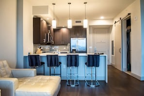 A modern kitchen with dark wooden cabinets, a central island with bar stools, and pendant lighting.
