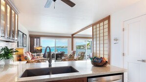 A kitchen with a large island, a dishwasher, and a view of the ocean.