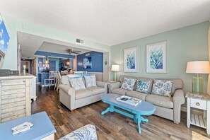 A living room with a sofa, coffee table, and a dining area with chairs and a table.