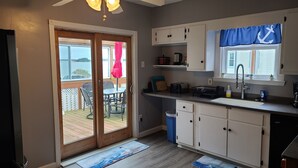 Una cocina con armarios blancos, una ventana con cortina azul y vistas al exterior.