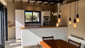 A modern kitchen with a wooden island, white cabinetry, and pendant lighting. - Modernes Ferienhaus in Erster Reihe Gegenüber der Dünen (Hourtin)