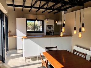 Una cocina moderna con una isla central, iluminación colgante y vistas amplias por un gran ventanal.