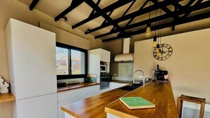 A modern kitchen with white cabinetry, a wooden countertop, a built-in oven, and a hanging light fixture. - Modernes Ferienhaus in Erster Reihe Gegenüber der Dünen (Hourtin)