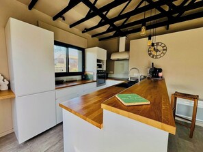 Une cuisine moderne avec un îlot central en bois, des meubles blancs et une fenêtre donnant sur l’extérieur.