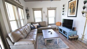 A living room with a leather sofa, a coffee table, a TV, and a bookshelf.