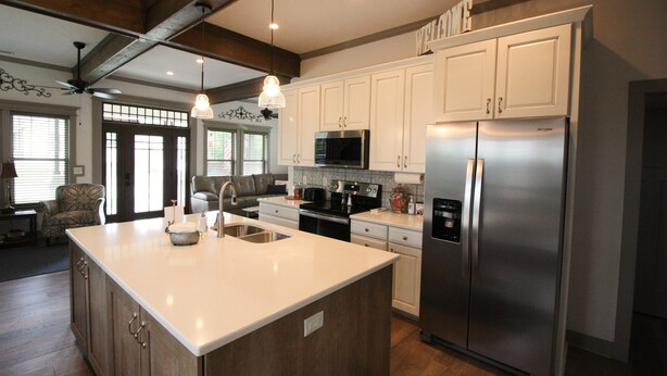 A modern kitchen with white cabinets, stainless steel appliances, and a large island.