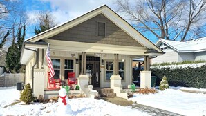 A two-story house with a covered porch, a mailbox, and a snowman decoration.
