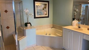 A bathroom with a bathtub, a shower, and a sink. There is a framed picture on the wall and a potted orchid on the counter. - Lovers Key Resort Suite 2 - Waterfront Views (Bonita Springs)