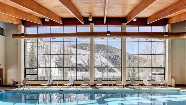 A large indoor swimming pool with clear views of a snowy mountain landscape through large windows. - Huge condo in Keystone, sleeps 14, great location (Dillon)