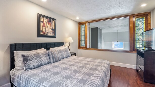 A bedroom with a bed, a nightstand, a lamp, a dresser, and a window with a view. - Huge condo in Keystone, sleeps 14, great location (Dillon)