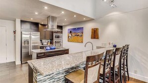 A modern kitchen with stainless steel appliances, a granite countertop, and a dining area with wooden chairs. - Huge condo in Keystone, sleeps 14, great location (Dillon)