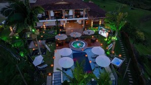 Un complexe hôtelier doté d’une piscine, d’un espace extérieur aménagé et d’une terrasse bien éclairée.
