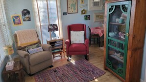A cozy living room with a red armchair, a beige sofa, a wooden cabinet, and a dining area with a table and chairs.