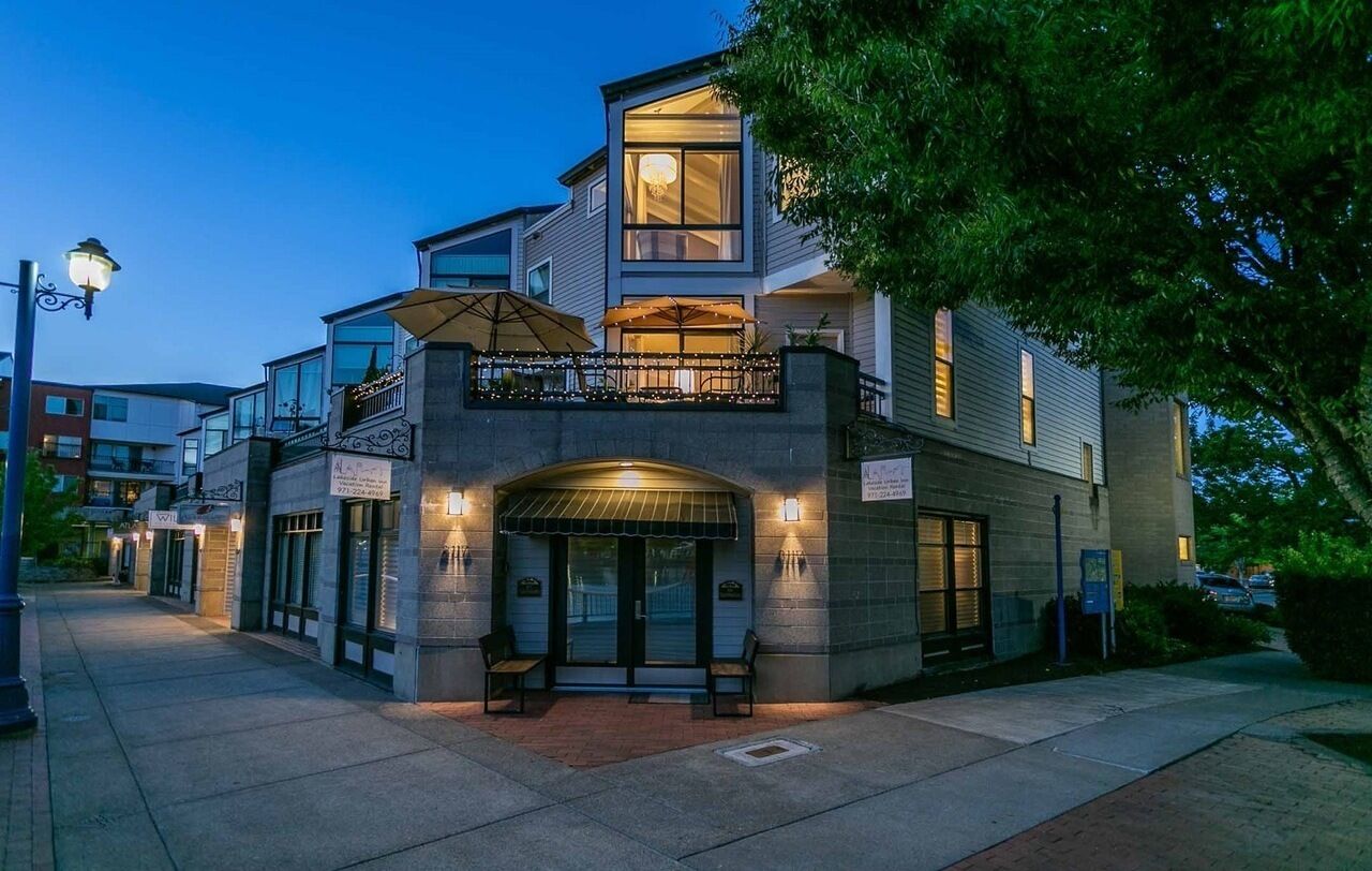 A modern building with a balcony, a covered entrance, and a well-lit facade.