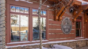 Una cabana de fusta amb un cartell que diu "Coffee Lab" i finestres que reflecteixen un paisatge nevós.