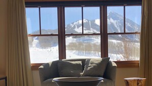Una habitació amb un finestral gran que ofereix vistes a un paisatge de muntanya nevada.