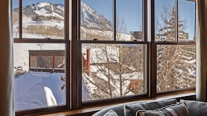 Una habitació amb un finestral gran que ofereix vistes a un paisatge de muntanya nevada.