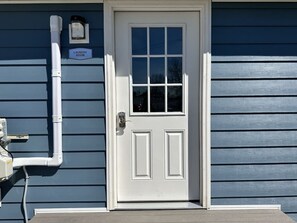 A white door with a window, a sign indicating a laundry room, and a white exterior wall.