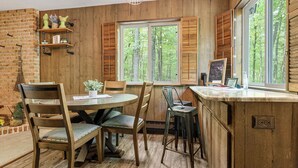 A wooden interior with a dining table, chairs, and a kitchen counter.