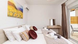 A modern hotel room with a large bed, a desk, and a painting on the wall. - South Beach Villas - 2 bedroom sea view with heated pool (Γεννάδι)
