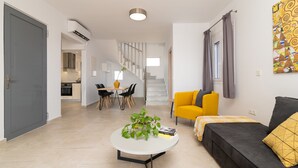 A modern living room with a sofa, coffee table, and a staircase leading to an upper floor. - South Beach Villas - 2 bedroom sea view with heated pool (Γεννάδι)