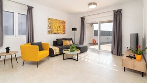 A modern living room with a yellow sofa, a grey sofa, a coffee table, a TV, and a potted plant. - South Beach Villas - 2 bedroom sea view with heated pool (Γεννάδι)