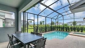 Ein überdachter Außenbereich mit Pool, Tisch und Stühlen sowie Blick auf die umliegende Landschaft.