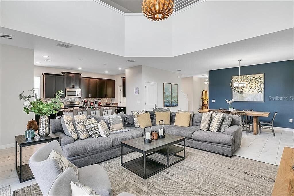A modern living room with a sectional sofa, a coffee table, and a dining area with a table and chairs.
