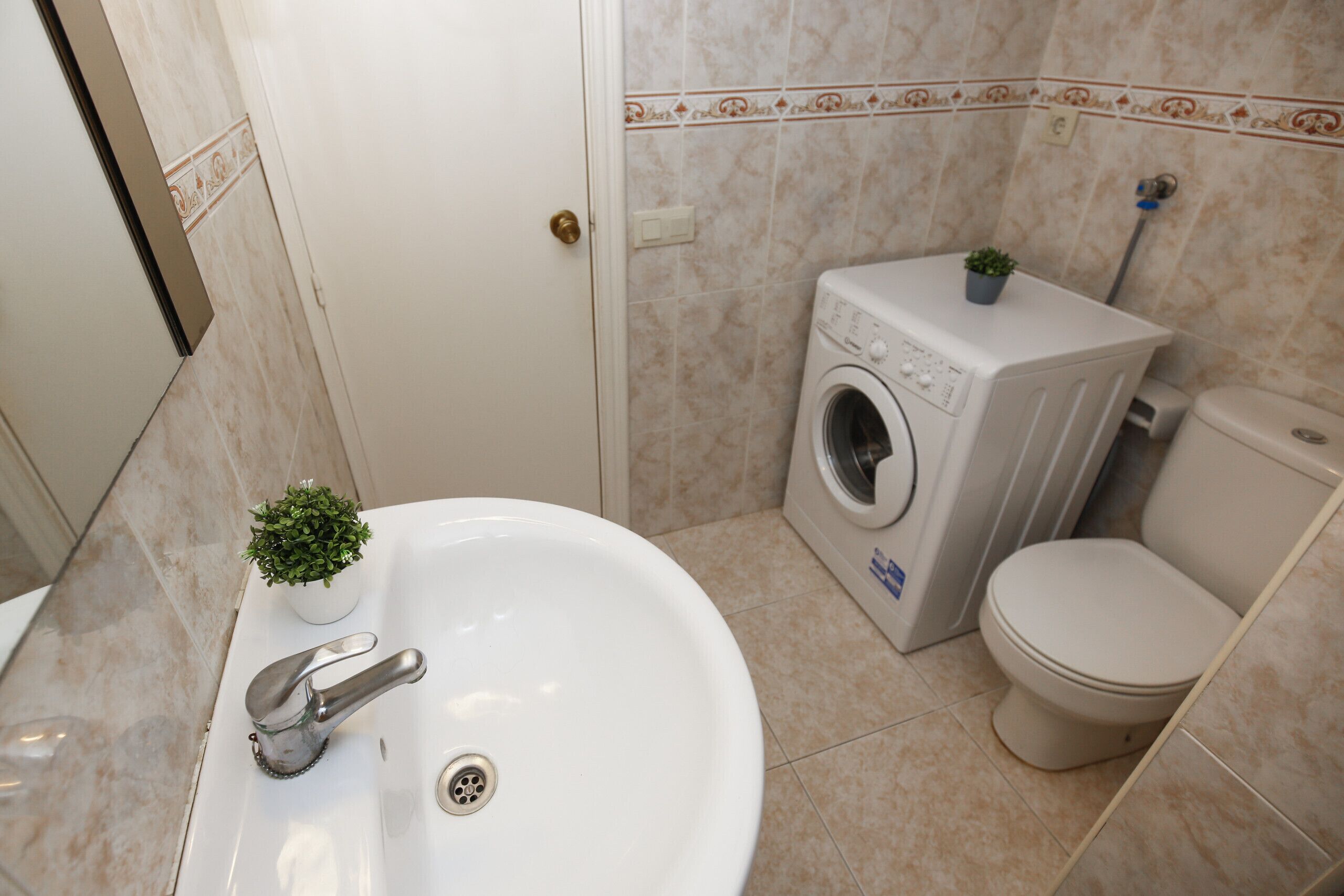 Kylpyhuone, jossa on pesuallas, pesukone ja wc.