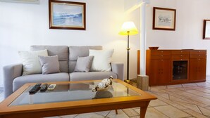 A living room with a sofa, a glass coffee table, a lamp, and a cabinet.