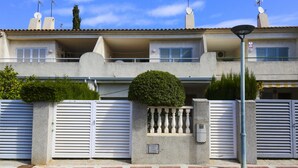 A two-story building with a gated entrance, a small balcony, and a satellite dish on the roof.