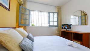 A hotel room with a bed, a desk, a television, and a window with curtains.