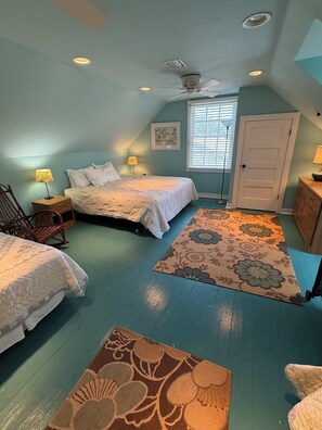 A bedroom with a bed, two nightstands, a chair, a door, and a window with blinds. - Historic Tucker Bay House (Fairhope)