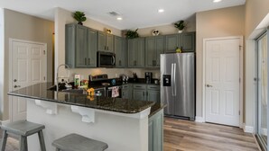 Una cocina moderna con gabinetes grises, electrodomésticos de acero inoxidable y una isla de encimera de granito.