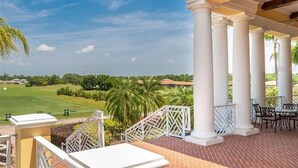 Un espacio al aire libre techado, con columnas blancas, suelo de ladrillo y mobiliario exterior.