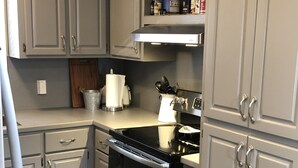 A kitchen with white cabinets, a stainless steel oven, and a countertop with various kitchen items. - Ly'an High Lodge - Venice Marina (Venice)