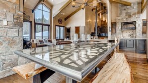 A spacious kitchen with a large island, stone walls, and a high ceiling with exposed beams.