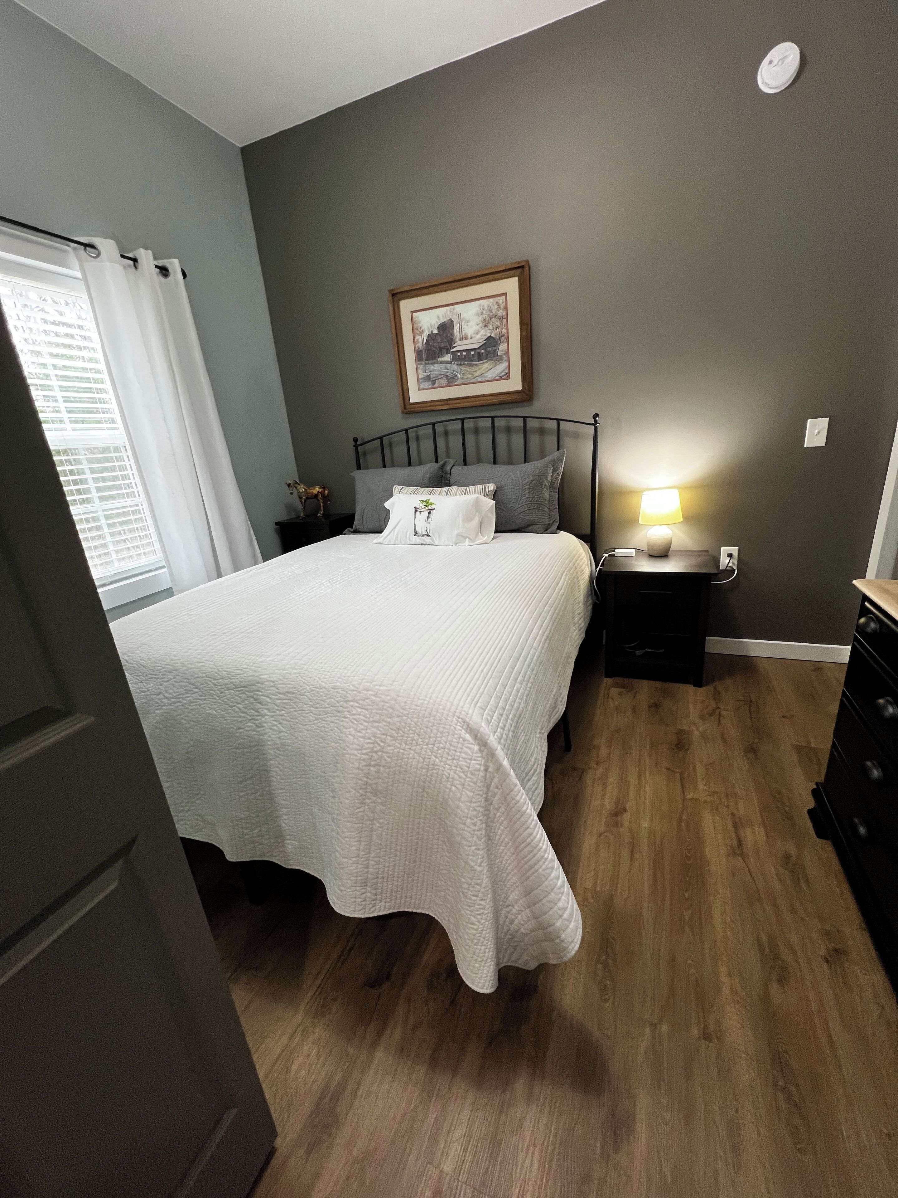 Une chambre à coucher avec un lit, une table de chevet, une lampe et un tableau au mur.