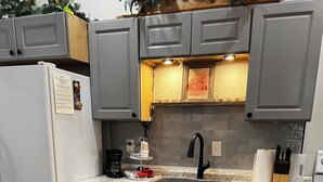 Een moderne keuken met grijze kastjes, een roestvrijstalen spoelbak en een ingebouwde kookplaat.