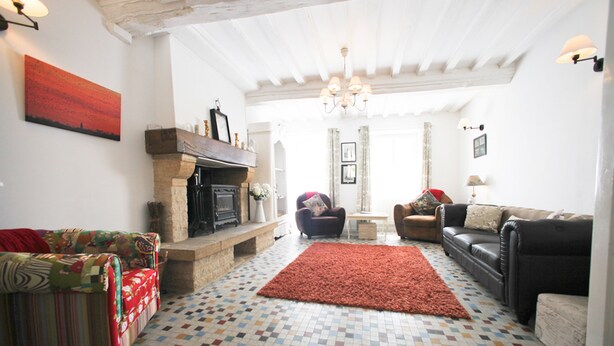 A living room with a fireplace, two sofas, a patterned rug, and a tiled floor.
