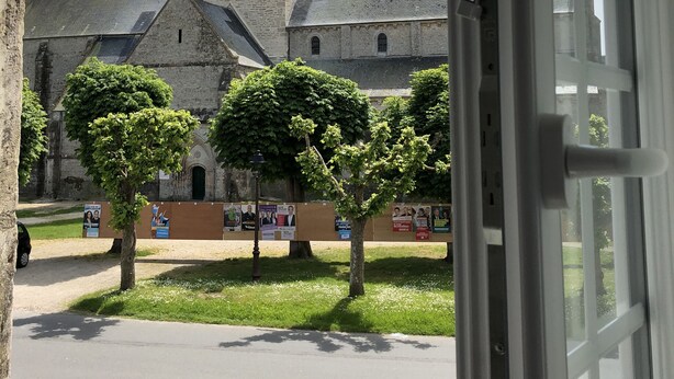 A historic building with a prominent tower and a courtyard with trees and banners.