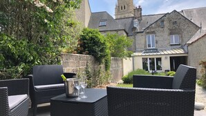An outdoor patio with wicker furniture and a table set with glasses and a pitcher.