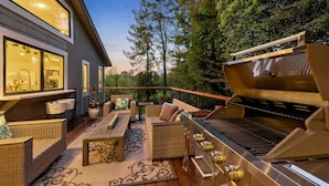 Eine Terrasse im Freien mit Korbm öbeln, einem Grill und Blick auf das Haus.