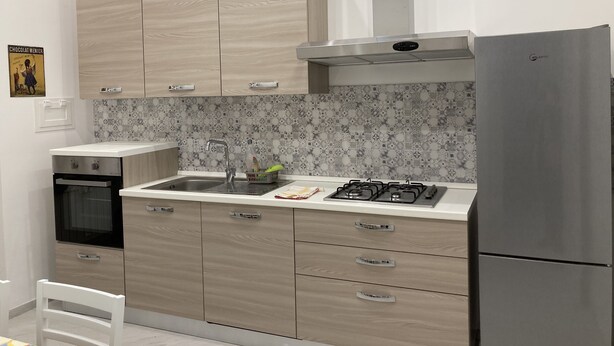 Une cuisine moderne avec des meubles de couleur bois clair, un évier en acier inoxydable, une cuisinière à gaz et un four encastré.