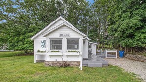 A small, single-story building with a gabled roof, a front porch, and a mailbox. - New Remodel! Updated Cottage near Beach and Park (Manistee)